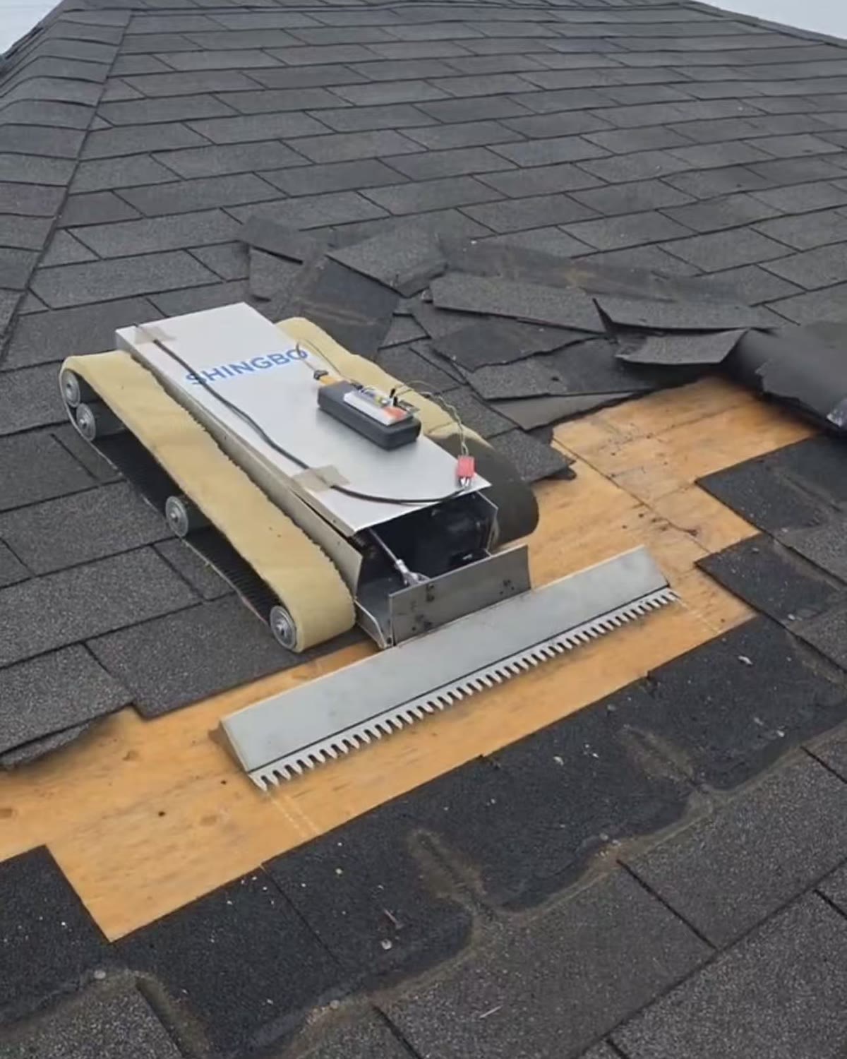 Shingbo roofing robot tearing off asphalt shingles down to the deck on a pitched roof